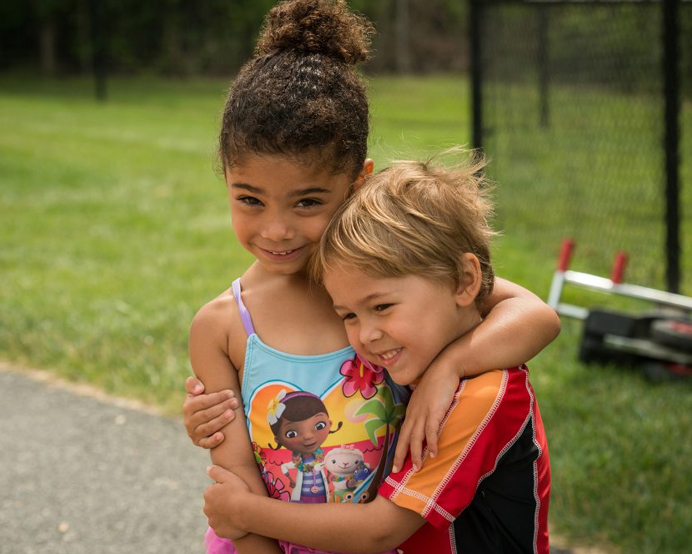 Two children hug outside at the Early Learning Center