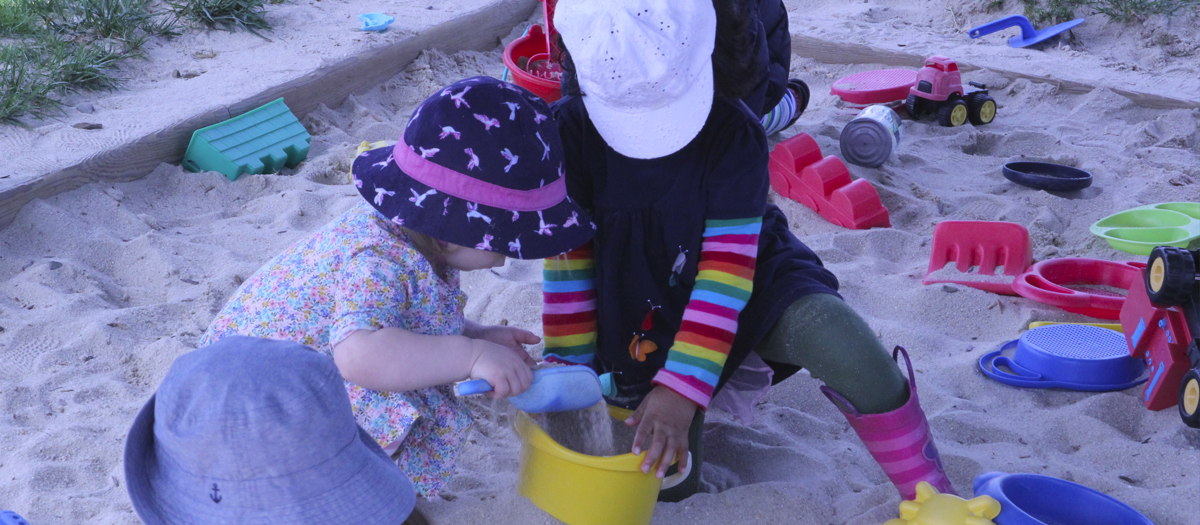 Two students play with pail and shovel in sandbox at the Early Learning Center