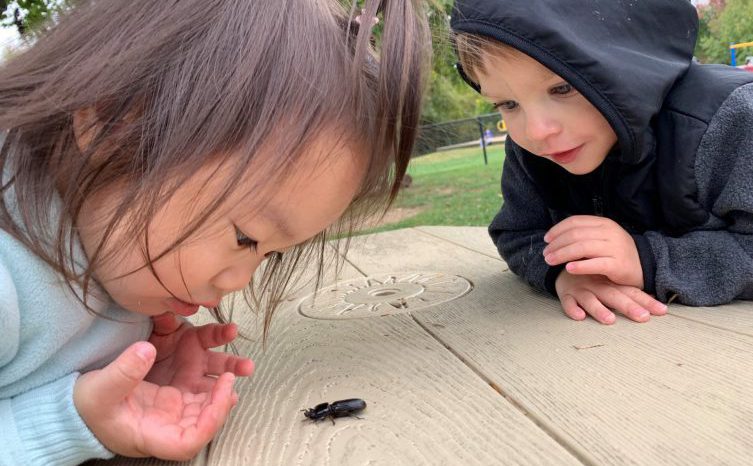 Two children read books outside at the University of Delaware Early Learning Center