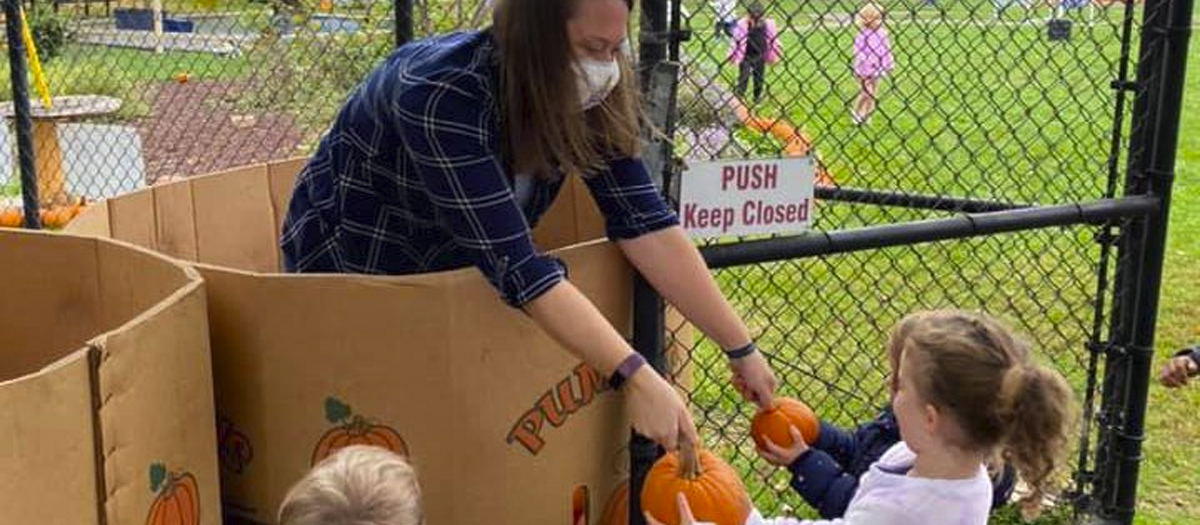 Teacher gives child a pumpkin at the Early Learning Center