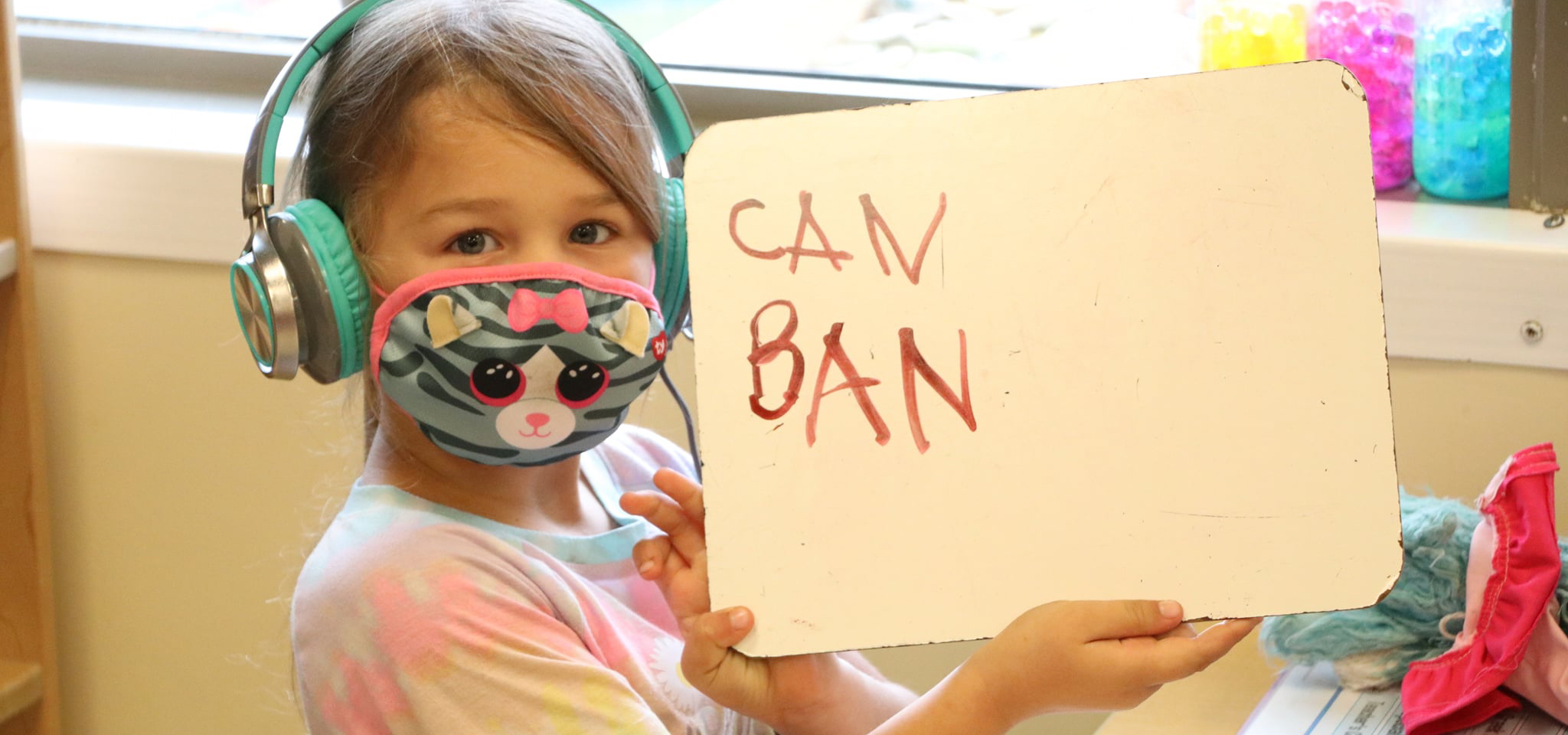 Girl holds up paper with writing on it at UD's Early Learning Center